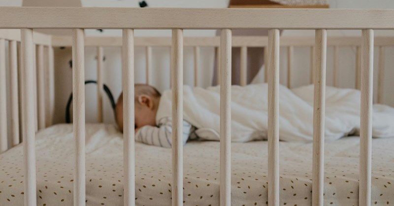A baby sleeping in a crib in her half-brother's bedroom