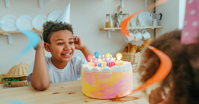 A little boy excited to blow out the candles at his 4th birthday party, despite the fact that his older sister is not here to celebrate with him.