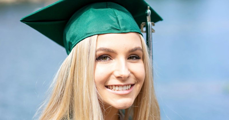 High school graduate smiles, content that her absent dad is not going to be at her high school graduation.