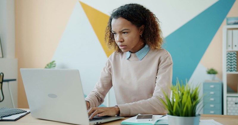 A young female employee works at her laptop after getting denied the promotion that she deserves.
