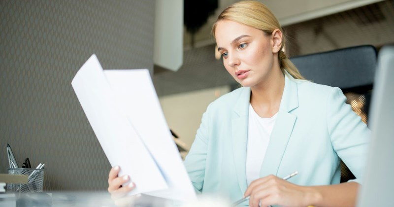 A young female employee looks over her bank statements, which show she's being paid less than she was before her supposed “raise.”