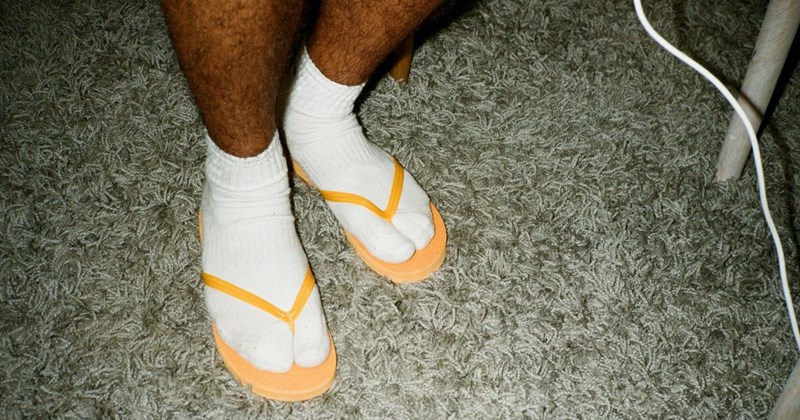 A young man, wearing socks and flip-flops, goes to work without seeing the problem with his attire.