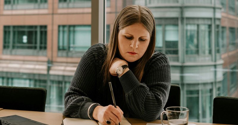 An employee is writing in her coworker's notebook while she's away from her desk.