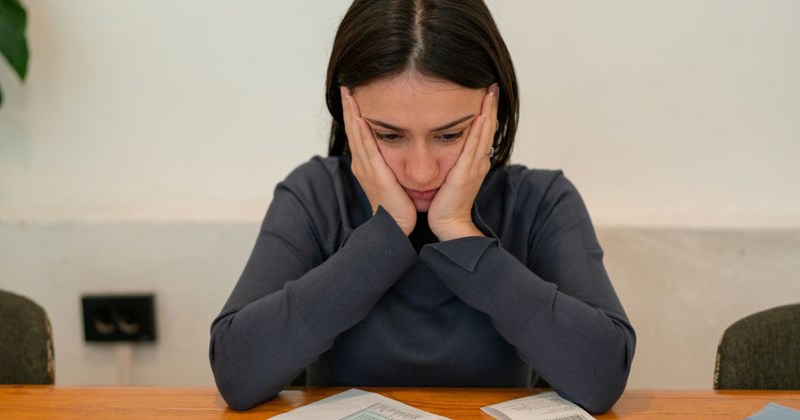 A young unemployed woman is stressed about her phone bills because she needs to pay them to attend a phone interview.