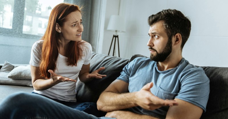 A man and a woman argue while sitting on a couch together