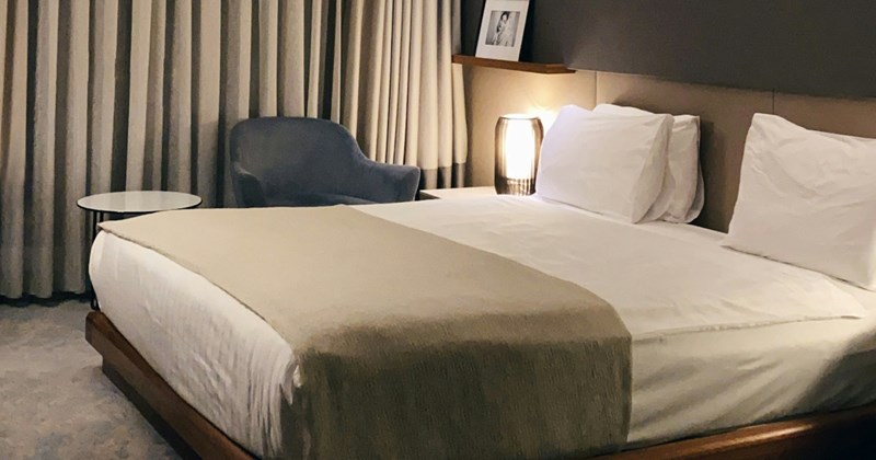 A neutral-colored hotel room with a king-size bed