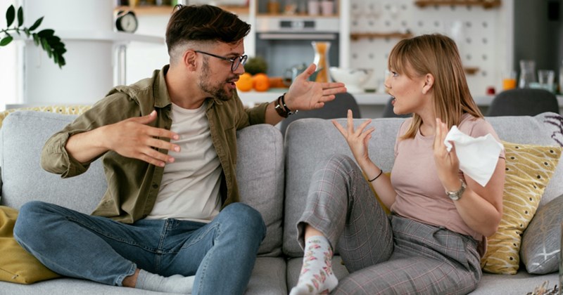 A representation of a man and a woman sitting on a couch, arguing with one another