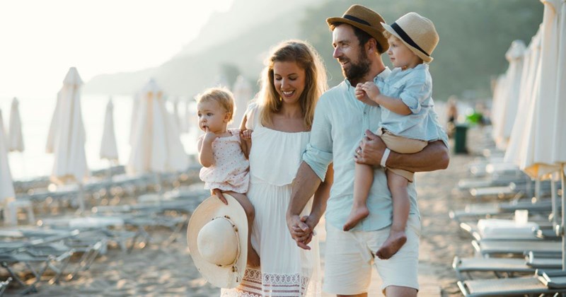 a young family on a beach vacation, enjoying each other's company while walking on the sand.