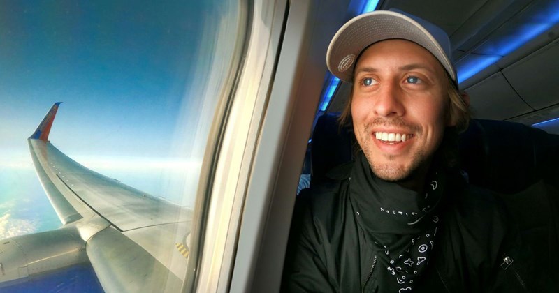 an airline passenger taking a selfie while looking out of the airplane window, excitedly thinking about his trip. 