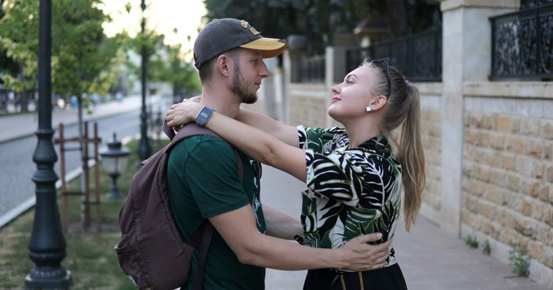 a boyfriend and girlfriend embracing outside of her house