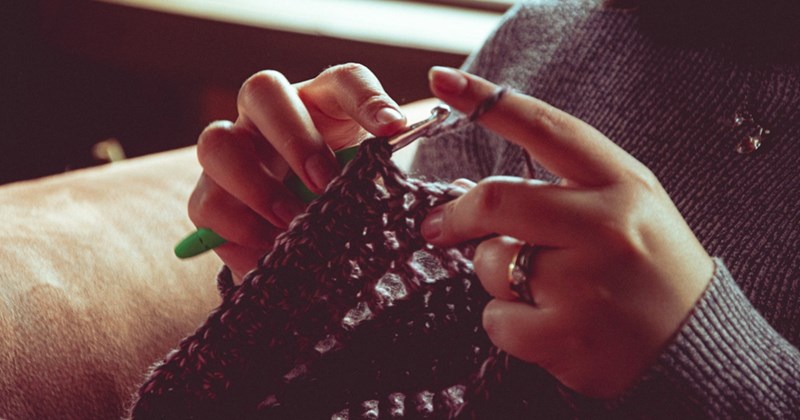A representation of a woman's hands crocheting while sitting down