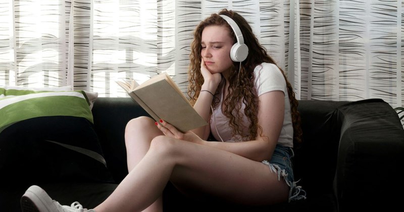 A teenage girl reads and listens to music instead of watching her half-sister because she's angry that her mom keeps having kids with her stepdad.