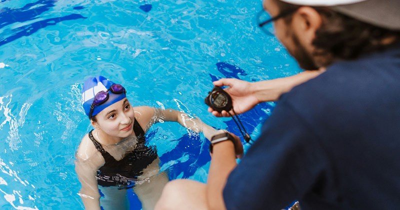 A lifeguard times a swimmer's swim test. 