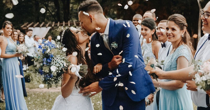 A bride and groom kiss each other after their wedding ceremony before they tell their guests that there are four different venues for the reception. 