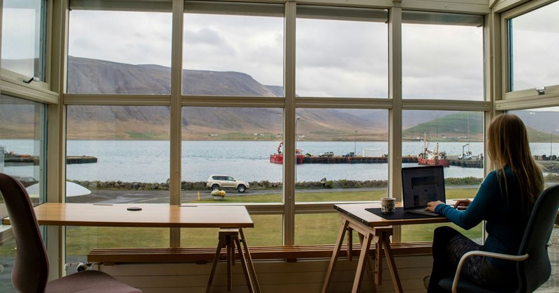 An employee working while her coworkers hang out with each other on a company retreat.