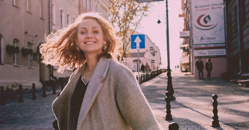   Title Description A young woman smiles and swings her hair while walking through a city street. 