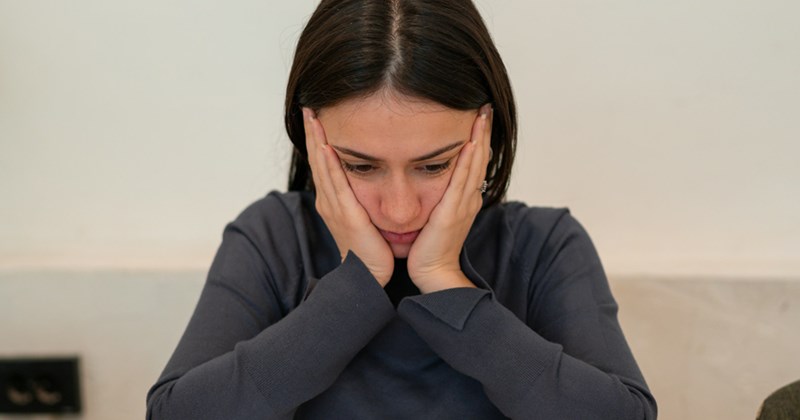 A woman sitting down with her hands on her face. 