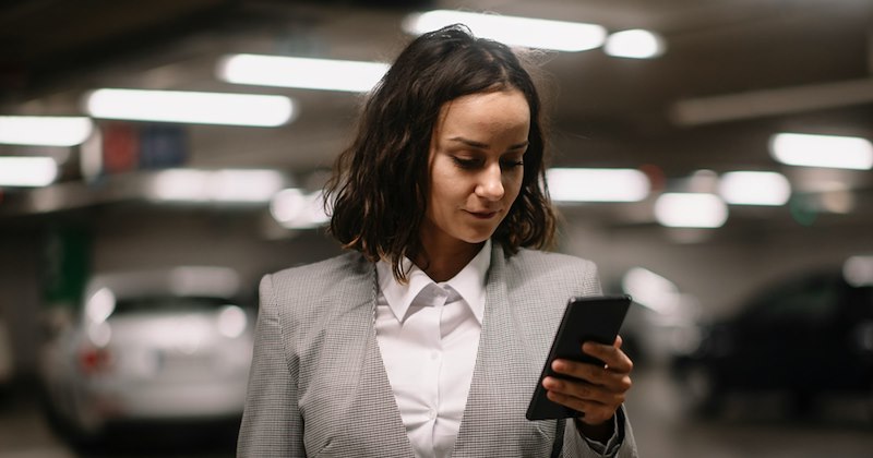 A job applicant checks her phone in a parking garage.
