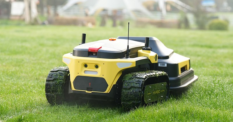 A robot lawnmower cuts grass in a backyard. 