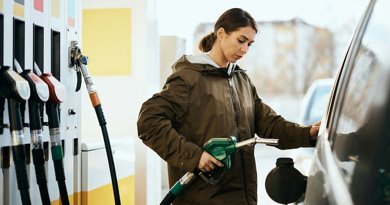 A young woman filling up her gas tank