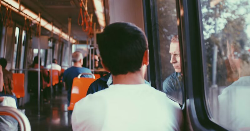 A teen in a white shirt rides the bus home