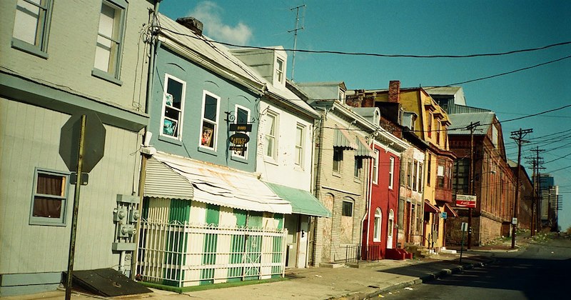 A street lined with colorful, old, run-down buildings and power lines. 