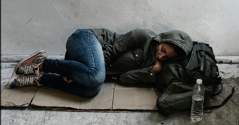 A homeless woman sleeping on the side of the street